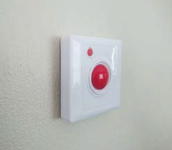 BellMe B-SW2 mounted on a wall, showing the large red call button and the small red cancel button