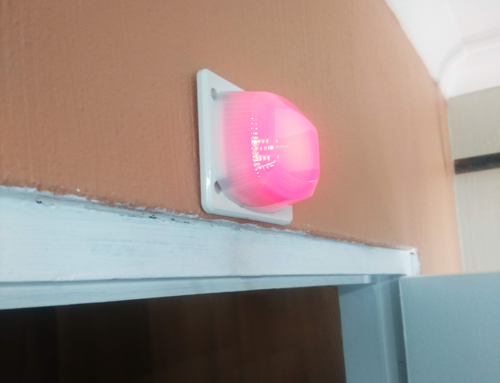 A BellMe B-700 LED Light installed above a door, flashing red